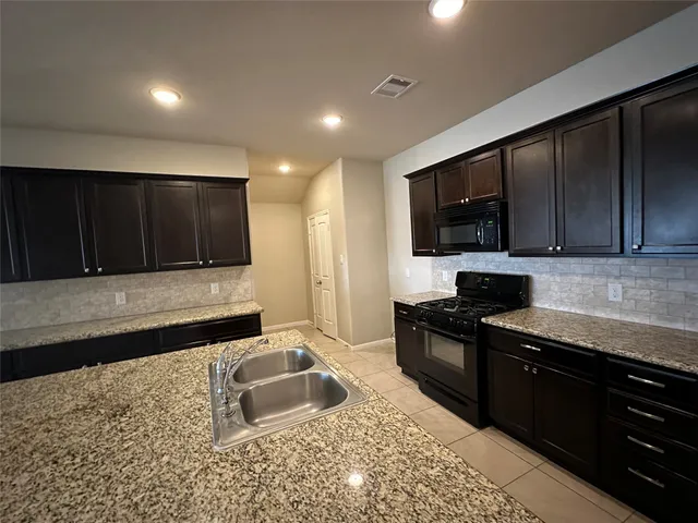 a kitchen with granite countertop wooden cabinets a stove top oven and granite counter tops