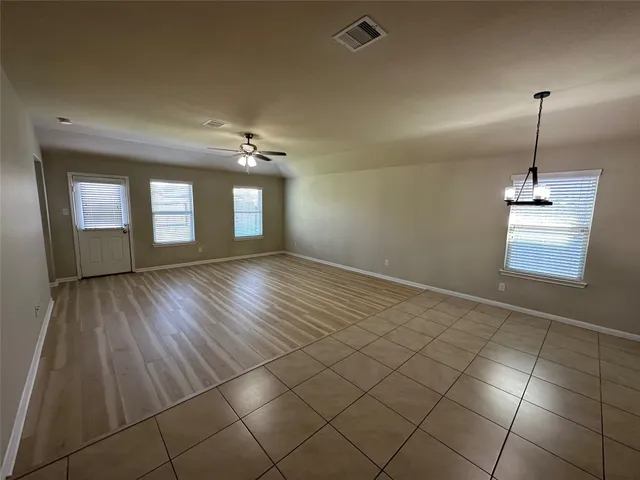 a view of an empty room with window and wooden floor