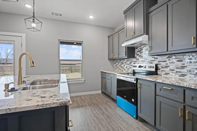 a kitchen with granite countertop a sink stainless steel appliances and cabinets