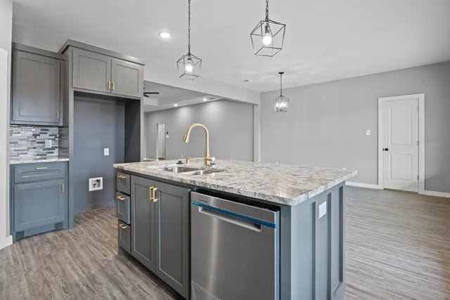 a kitchen with a sink stainless steel appliances and wooden floor