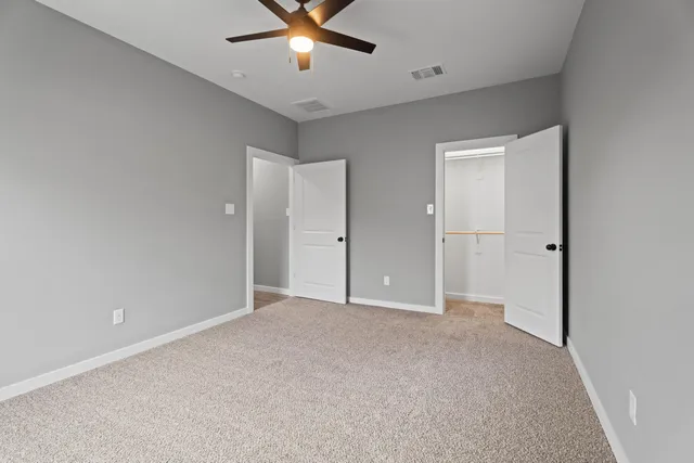 an empty room with closet and a chandelier fan