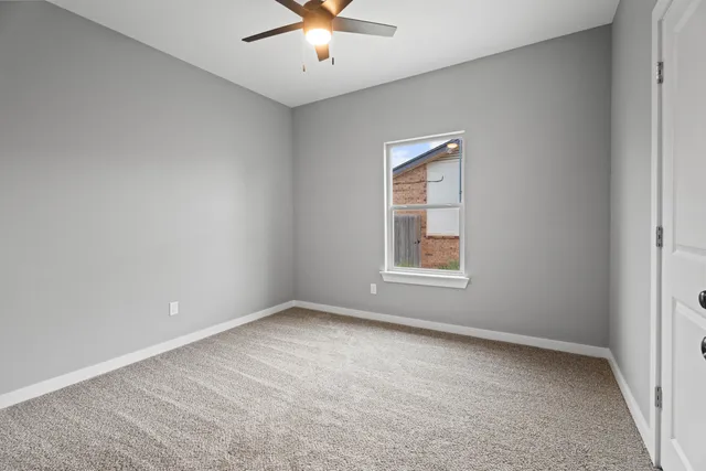 an empty room with chandelier fan and windows
