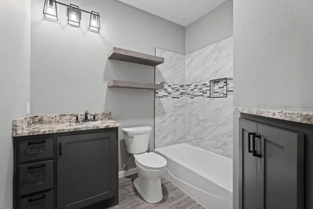 a bathroom with a granite countertop sink toilet and shower