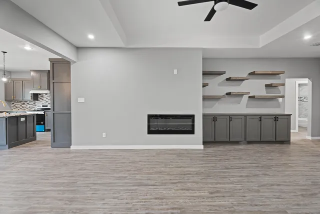 a view of a kitchen with kitchen island stainless steel appliances a sink cabinets and a fireplace