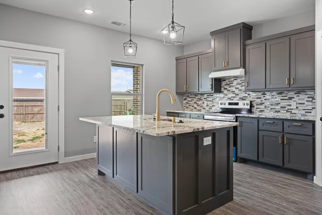 a kitchen with kitchen island granite countertop a sink cabinets and wooden floor