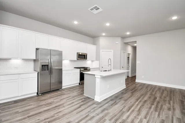 a kitchen with stainless steel appliances a sink cabinets and wooden floor
