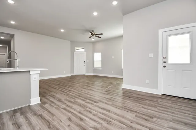 an empty room with wooden floor and a kitchen space