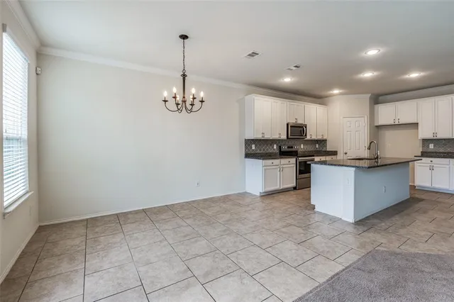 a kitchen with kitchen island granite countertop stainless steel appliances a sink a counter top space cabinets and a window