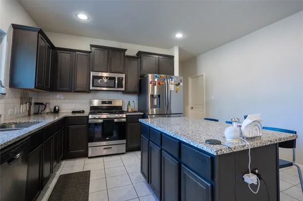 a kitchen with stainless steel appliances granite countertop a stove refrigerator and a sink