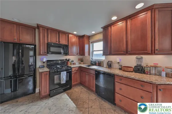 a kitchen with granite countertop wooden cabinets stainless steel appliances and a window