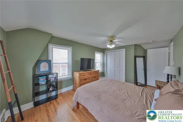 a bedroom with a bed a mirror on dresser and a wooden floor