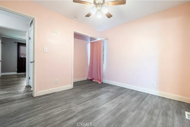 an empty room with wooden floor and fan