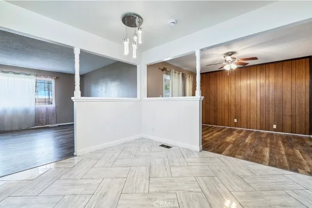 a view of an empty room with wooden floor and a kitchen