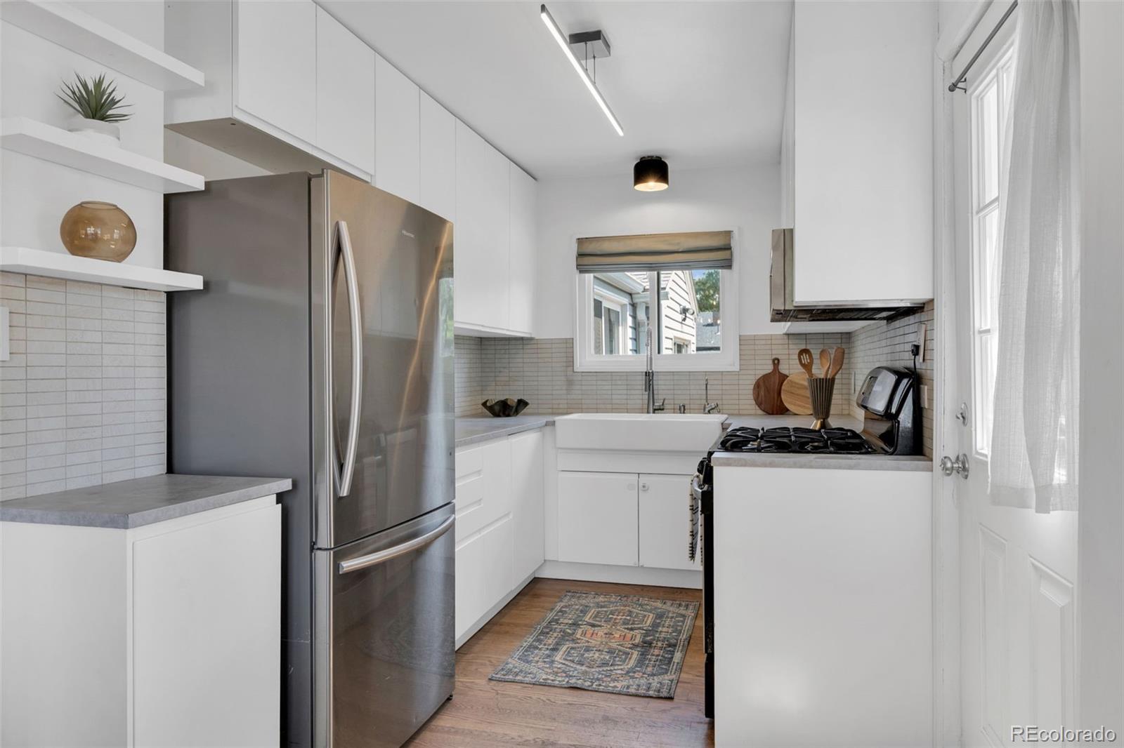 2900 Benton Street Wheat Ridge, CO 80214 - Photo 10 of 43 a kitchen with stainless steel appliances granite countertop a refrigerator a stove and a sink with large windows