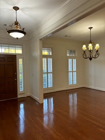 a view of an room with wooden floor chandelier and windows