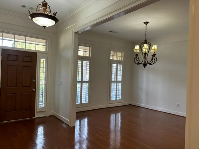 a view of a room with wooden floor chandelier and windows