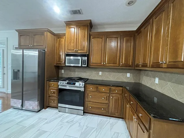 a kitchen with stainless steel appliances granite countertop a stove a sink and a refrigerator