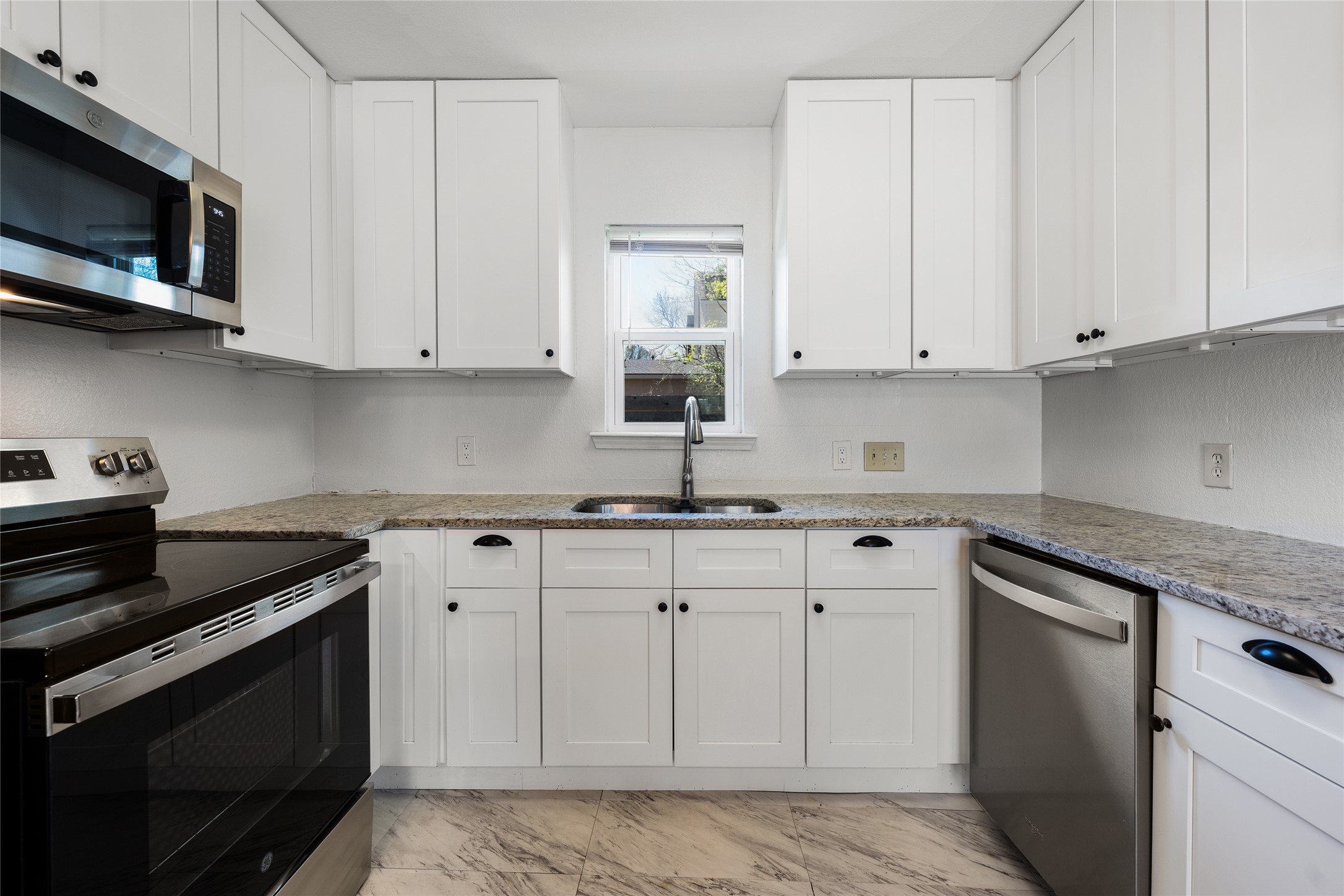 1116 Ebert Avenue, Unit B Austin, TX 78721 - Photo 5 of 28 a kitchen with stainless steel appliances granite countertop white cabinets a sink and dishwasher