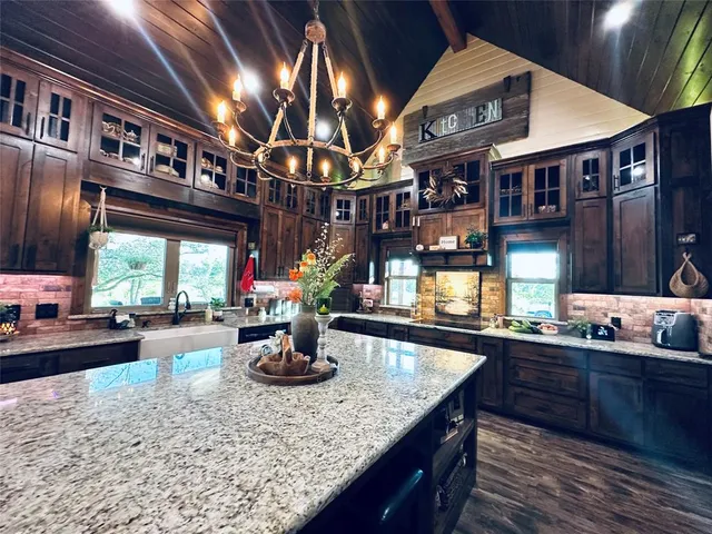 a large room with stainless steel appliances kitchen island granite countertop a table chairs and a refrigerator