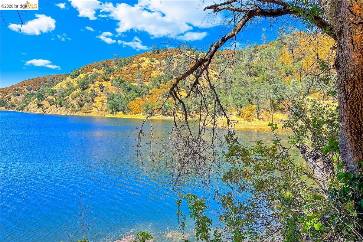 14450 Jacksonville Road Jamestown, CA 95327 - Photo 80 of 85 Expansive water body bordered by sloping hillsides, featuring diverse natural foliage and a vibrant blue sky with scattered clouds