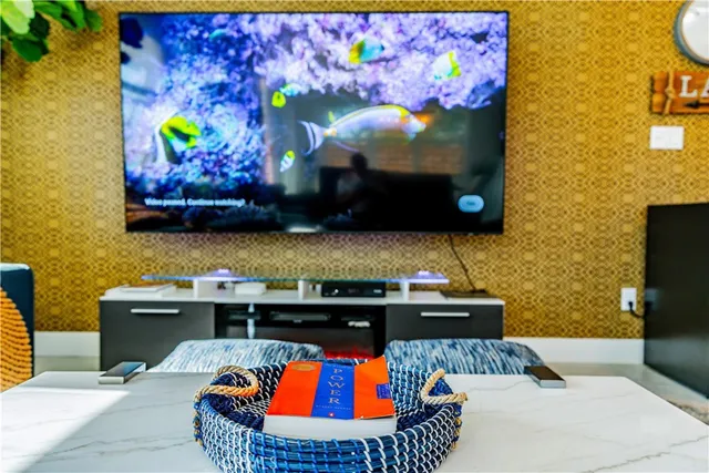 a living room with stainless steel appliances kitchen island granite countertop a couch and a flat screen tv
