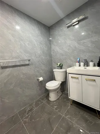 a bathroom with a white toilet sitting next to a white sink and vanity