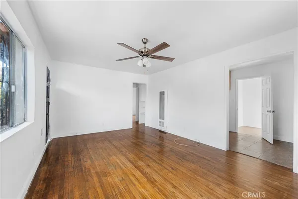 an empty room with wooden floor and a ceiling fan