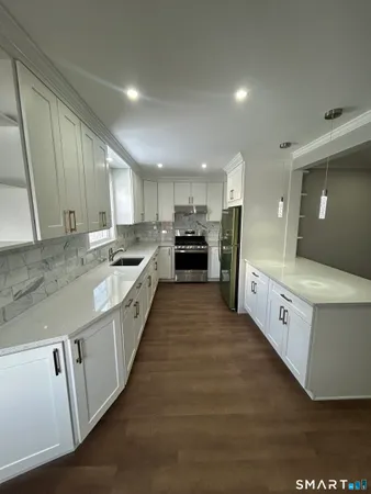 a large kitchen with granite countertop a large counter top and stainless steel appliances