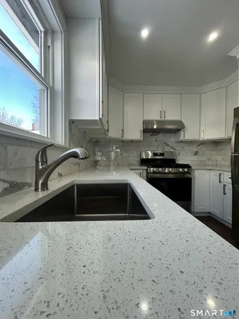a kitchen with granite countertop a sink a stove and cabinets