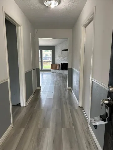 a view of a hallway with wooden floor and a living room
