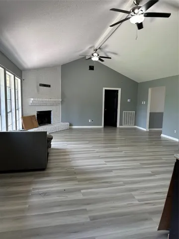 a view of a livingroom with a fireplace a chandelier a ceiling fan and wooden floor