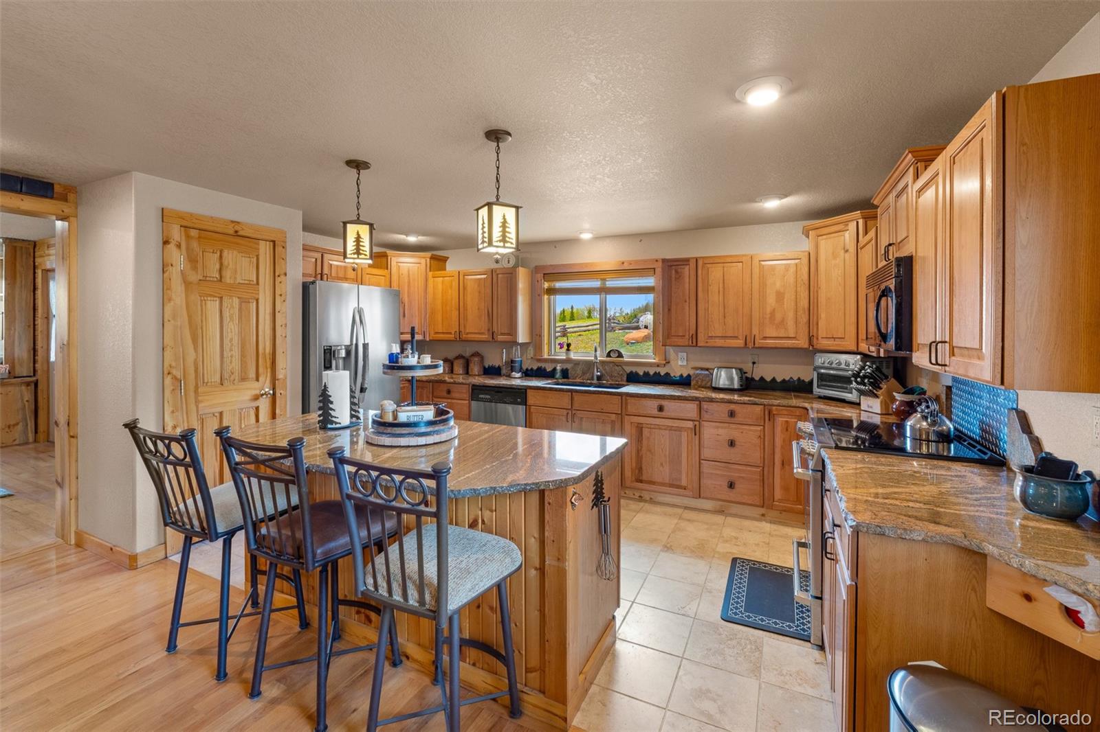 1163 Michigan Hill Road Jefferson, CO 80456 - Photo 9 of 48 a kitchen with stainless steel appliances a dining table chairs and granite counter tops