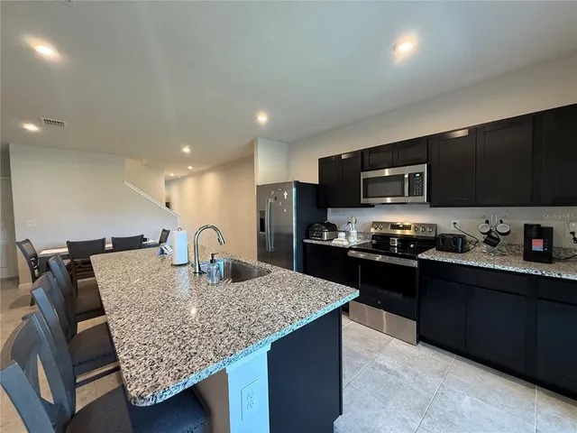 a kitchen with stainless steel appliances granite countertop a kitchen island hardwood floor sink stove refrigerator and cabinets