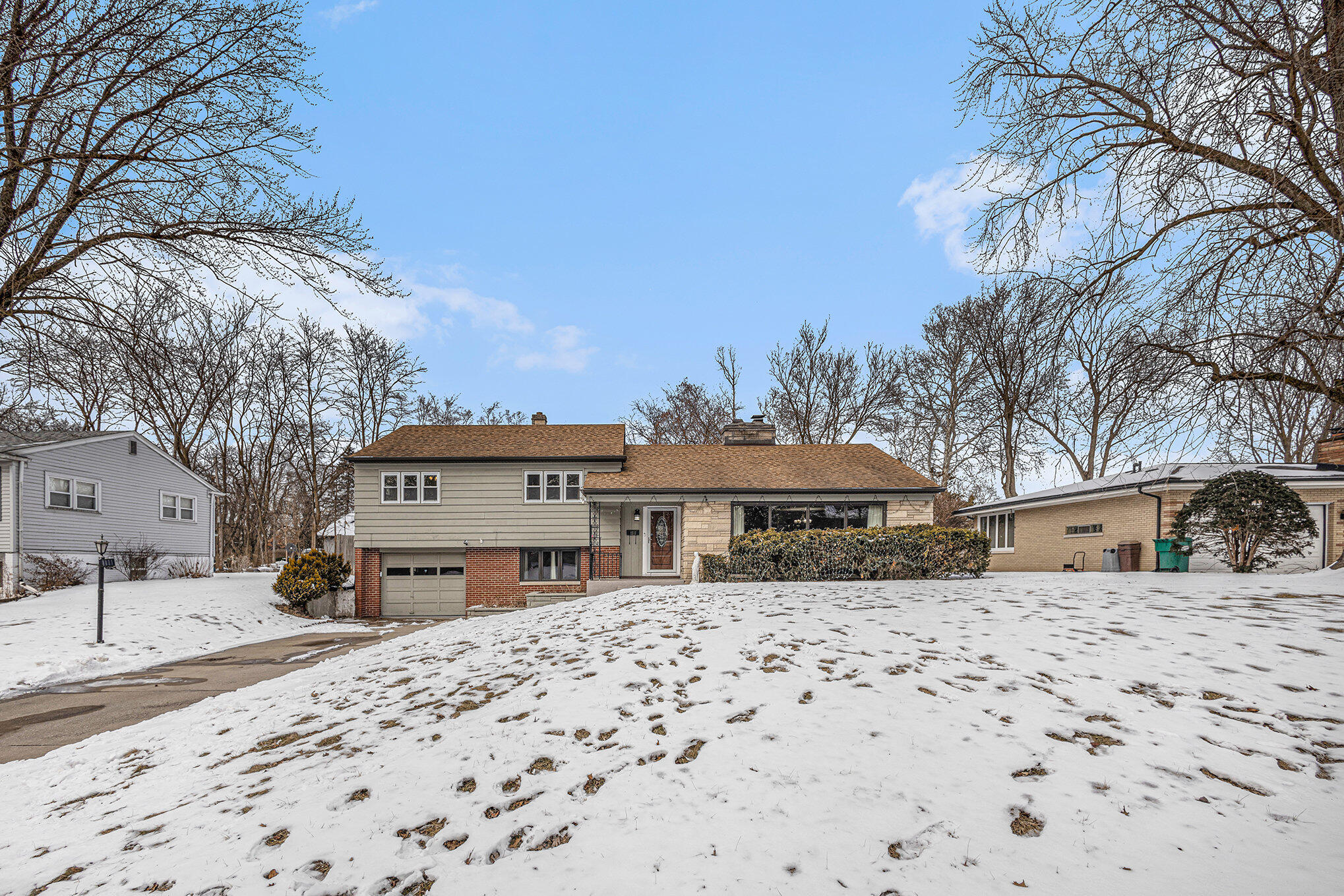 a front view of a house with a yard covered in snow