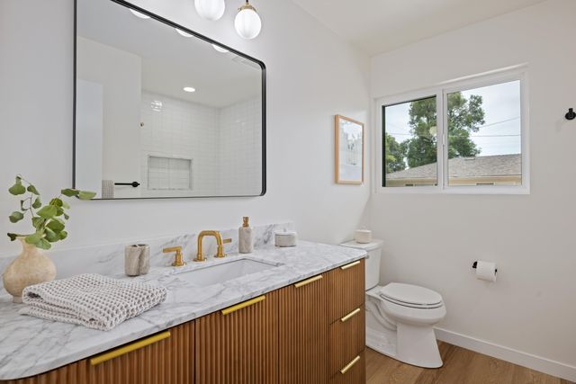 a bathroom with a granite countertop sink mirror and toilet