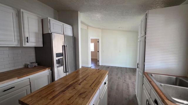 1450 North Dixie Downs Road, Unit 51 St. George, UT 84770 - Photo 5 of 25 Kitchen featuring wood-finish countertops, white cabinetry with dark hardware, a stainless steel refrigerator, and subway tile backsplash