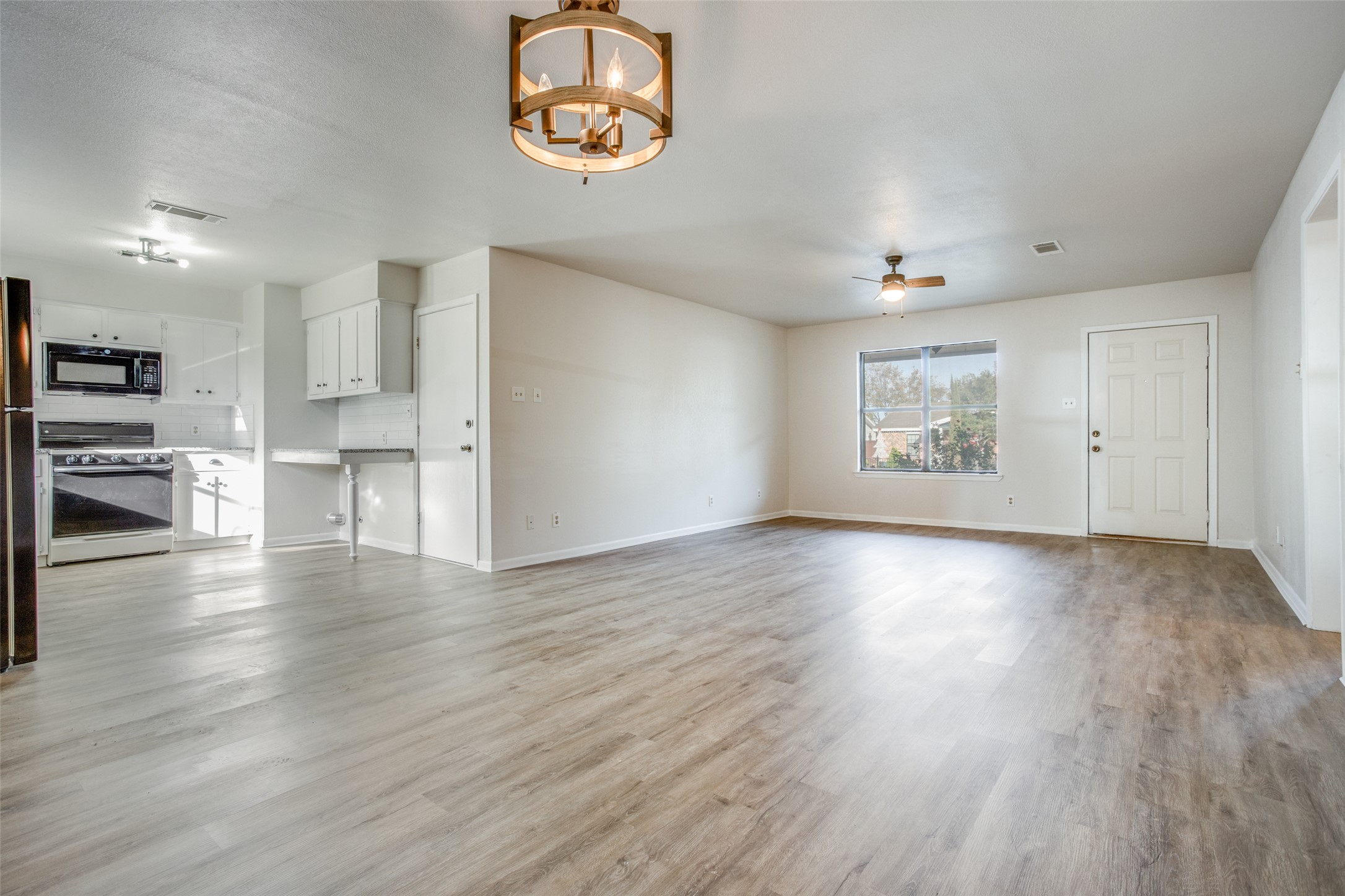 2212 Rifle Bend Drive Georgetown, TX 78626 - Photo 4 of 15 an empty room with wooden floor kitchen view and a window