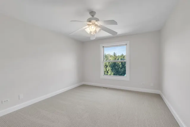 an empty room with a window and a fan