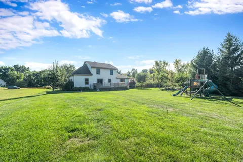 a view of a house with a big yard and basketball court