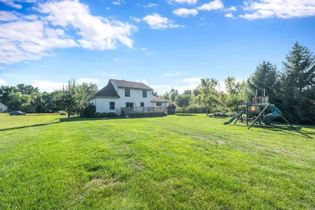 a view of a house with a big yard and basketball court