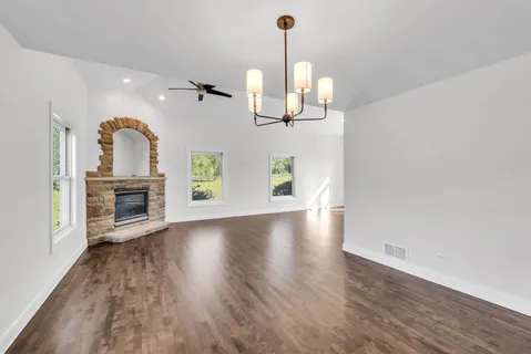 a view of a room with wooden floor fireplace and windows