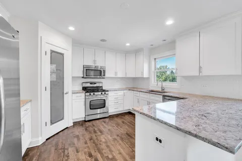 a kitchen with granite countertop white cabinets and stainless steel appliances