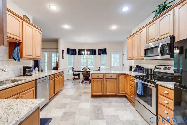 a kitchen with stainless steel appliances granite countertop wooden cabinets a sink dishwasher a stove and a refrigerator with wooden floor