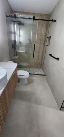 a bathroom with a granite countertop sink a toilet and shower