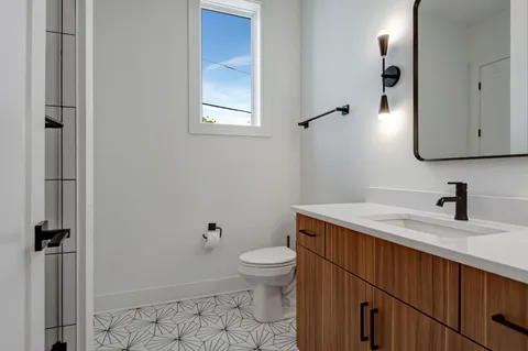 a bathroom with a granite countertop sink toilet and mirror