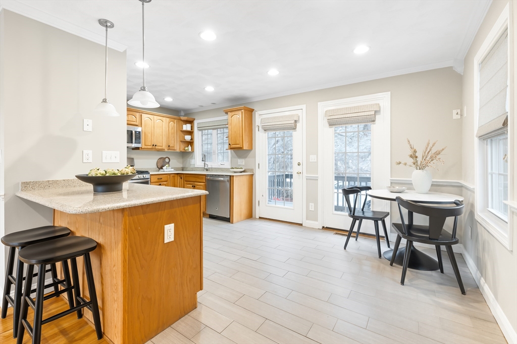 70 Sylvan Street, Unit 70 Melrose, MA 02176 - Photo 6 of 20 a kitchen with stainless steel appliances granite countertop table chairs and a refrigerator