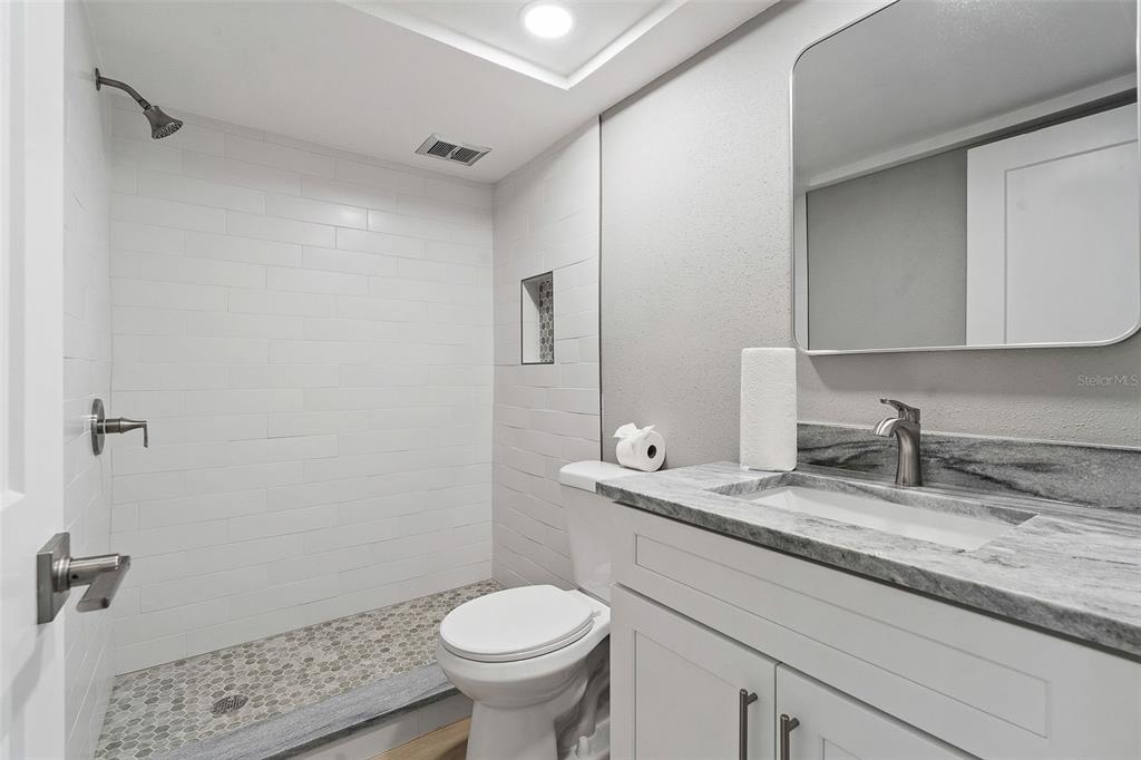 1 Boca Ciega Point Boulevard, Unit 113 St. Petersburg, FL 33708 - Photo 13 of 36 a bathroom with a granite countertop sink toilet and mirror