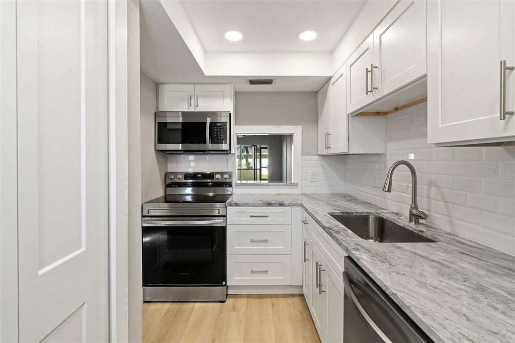1 Boca Ciega Point Boulevard, Unit 113 St. Petersburg, FL 33708 - Photo 7 of 36 a kitchen with stainless steel appliances granite countertop a stove and a sink