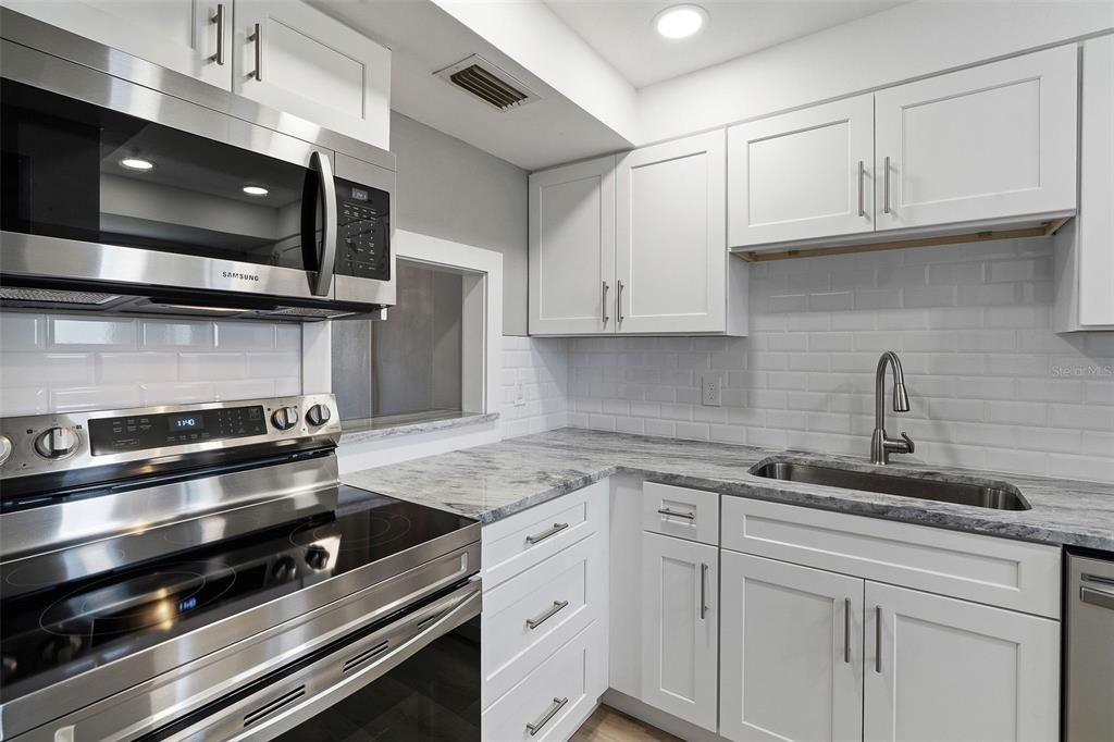 1 Boca Ciega Point Boulevard, Unit 113 St. Petersburg, FL 33708 - Photo 8 of 36 a kitchen with stainless steel appliances granite countertop a sink and a stove