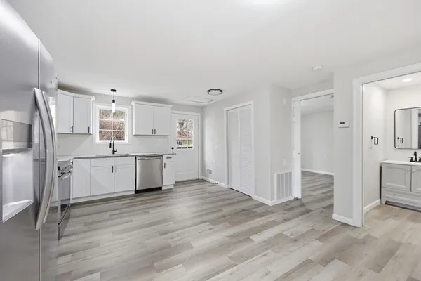 a kitchen with stainless steel appliances granite countertop a stove top oven a sink dishwasher and a refrigerator with wooden floor